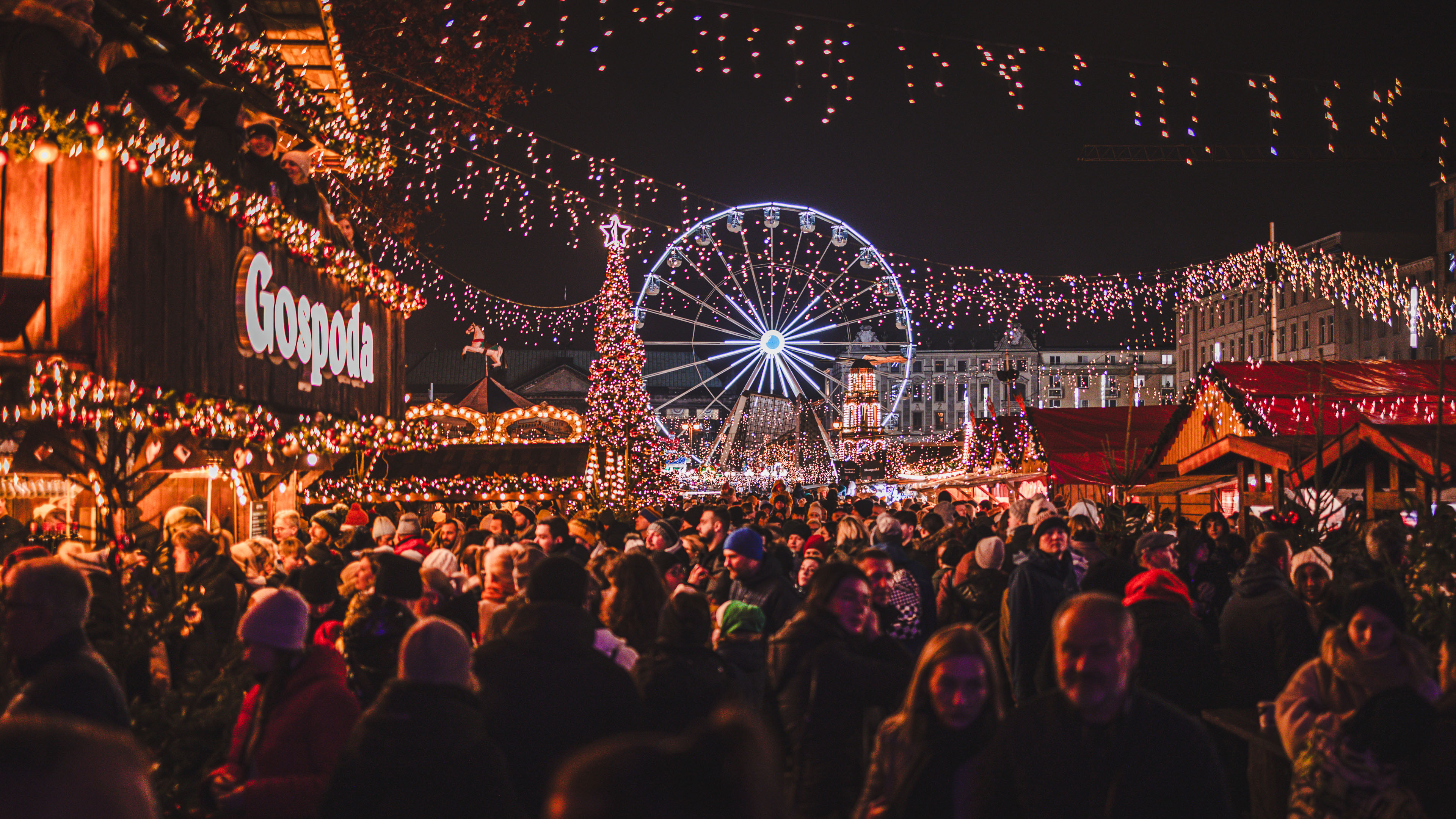 Tłum ludzi na świątecznym jarmarku z diabelskim młynem i ozdobami